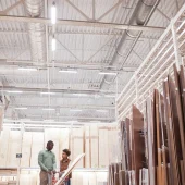 Vertical wide angle portrait of African-American father and son shopping together in hardware store standing with cart in wood and boards isle, copy space